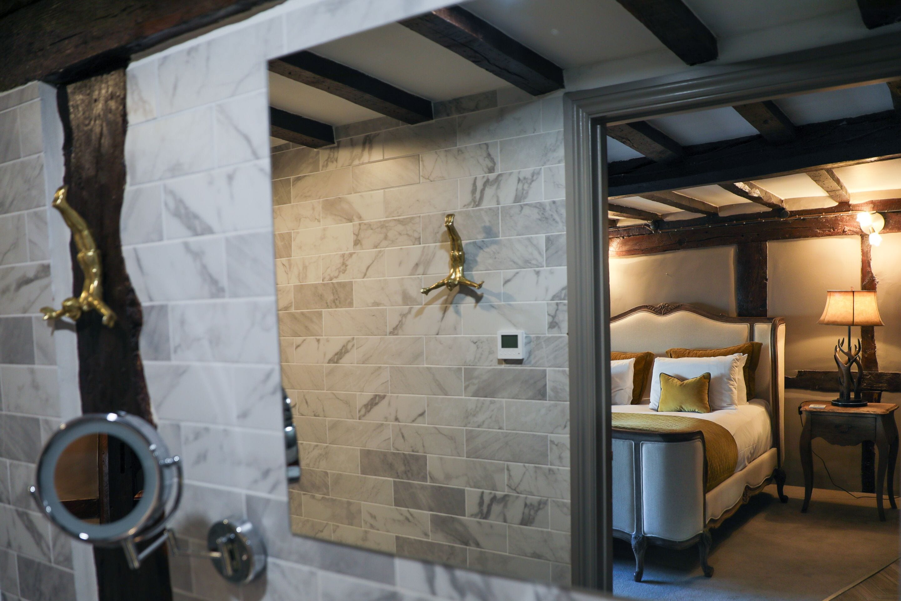 A bedroom with a marble wall, a bed with white bedding, a nightstand, and a lamp.