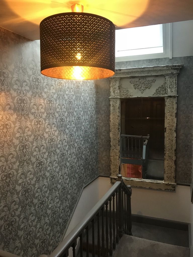 Un escalier orné d’un papier peint décoratif et doté d’une rampe en métal ouvragée.