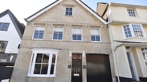 A two-story stone building with a black front door, a bay window, and a sign indicating a business on the ground floor. - The Kingsbury at No7 & No8 (Marlborough)