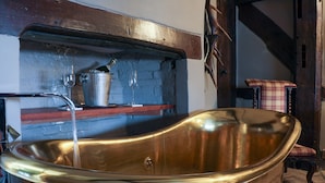 A vintage bathtub with a wooden shelf above it, a metal bucket, and a chair in the background. - The Kingsbury at No7 & No8 (Marlborough)