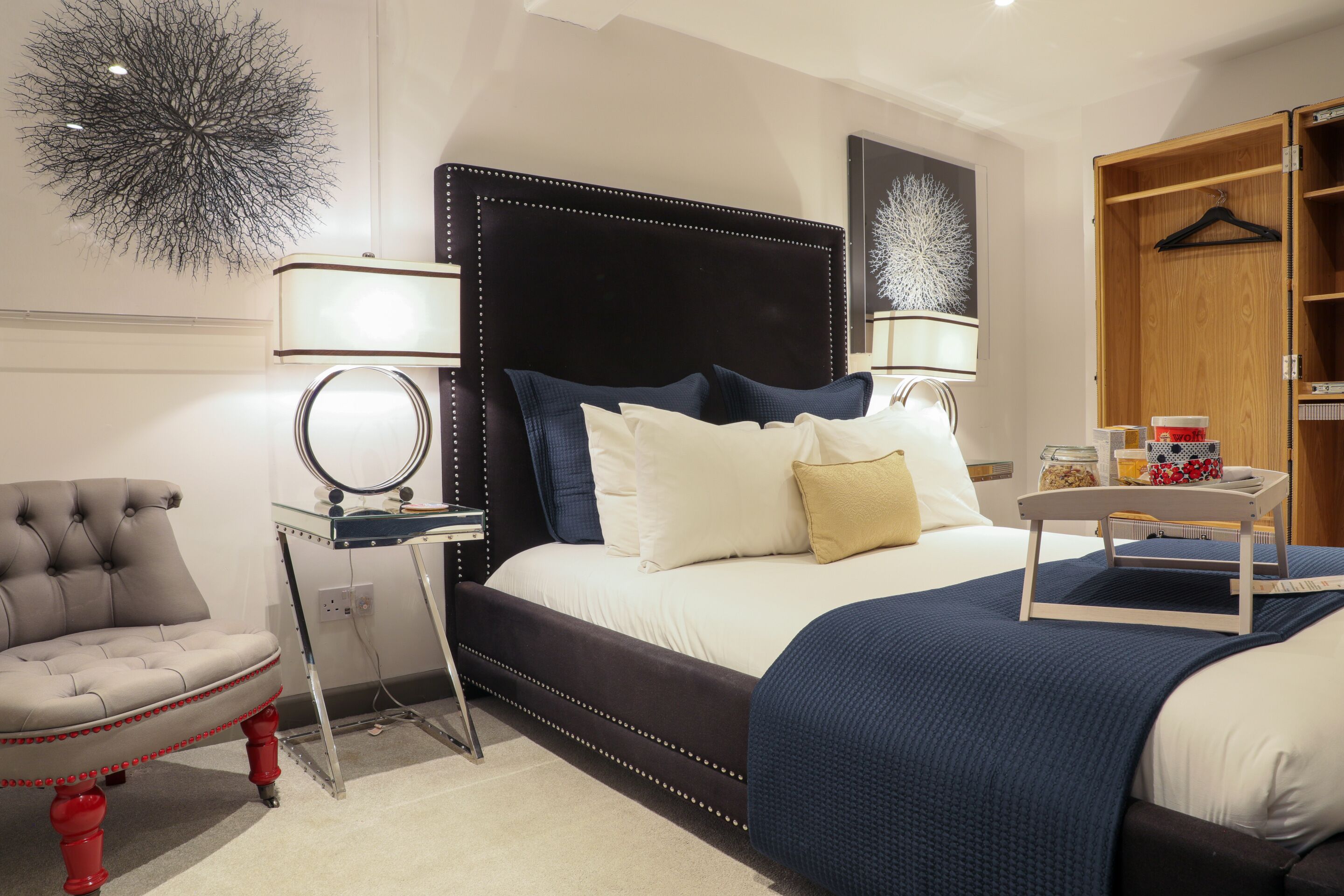 Een keurig opgemaakt slaapkamer met een groot bed, nachtkastjes, een stoel en een kledingkast.