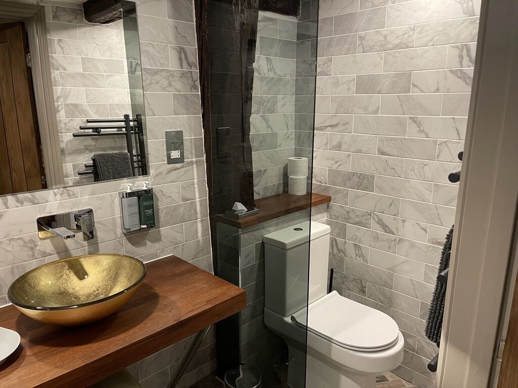 A modern bathroom with a large glass sink, a toilet, and a shower area.