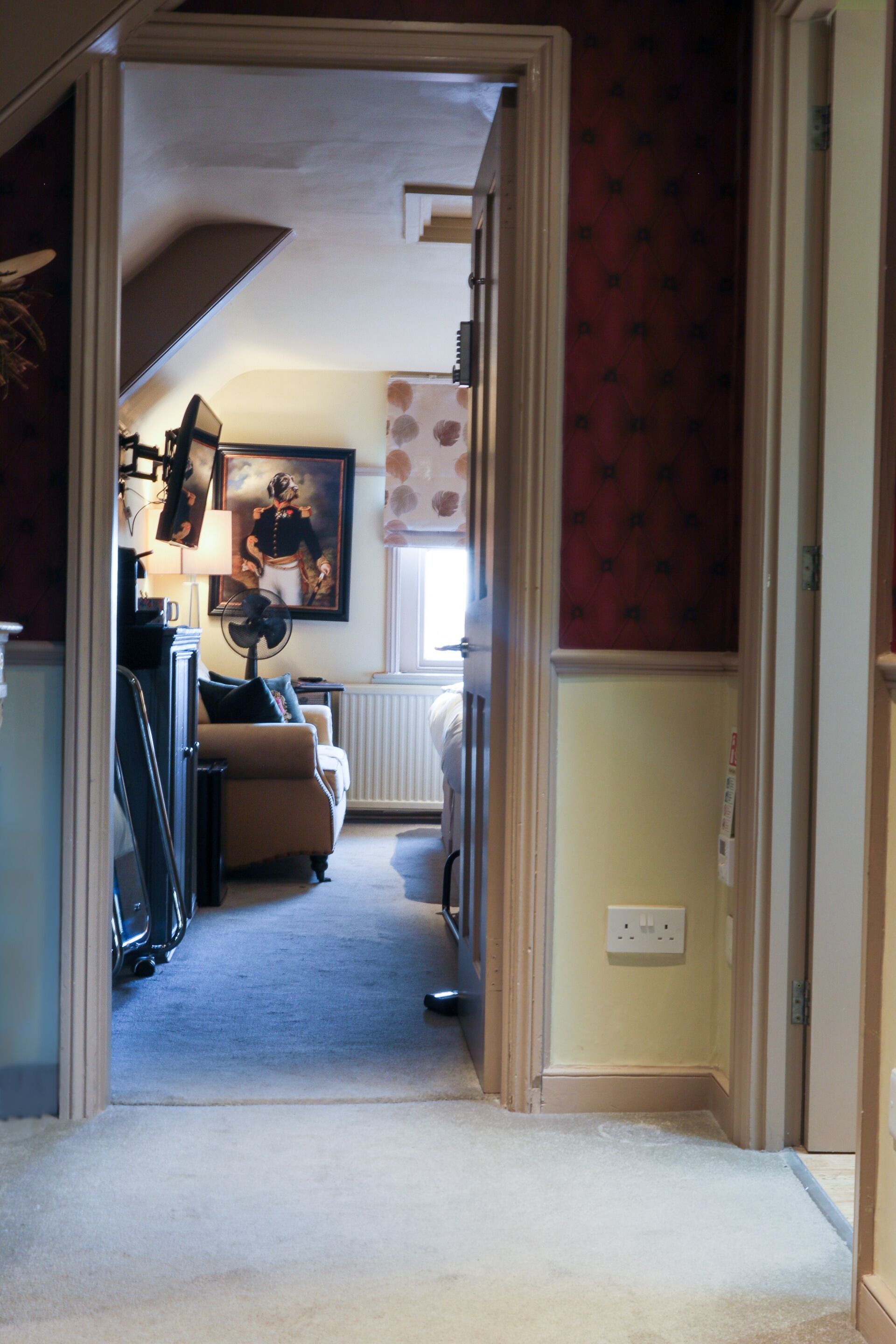 A hallway leading to a living room with a sofa, a lamp, and a framed picture on the wall.