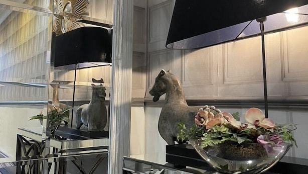 A modern interior with a glass table, a black lamp, and decorative items including a horse statue and plants. - The Kingsbury at No7 & No8 (Marlborough)