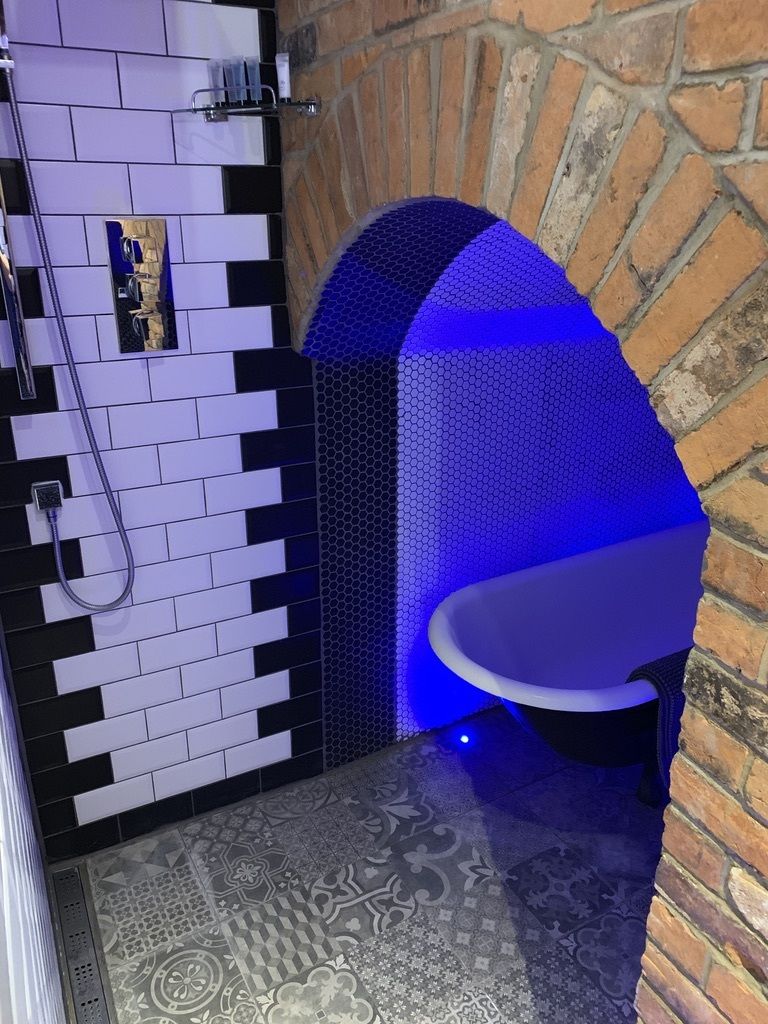 A bathroom with a shower, a toilet, and a patterned floor.