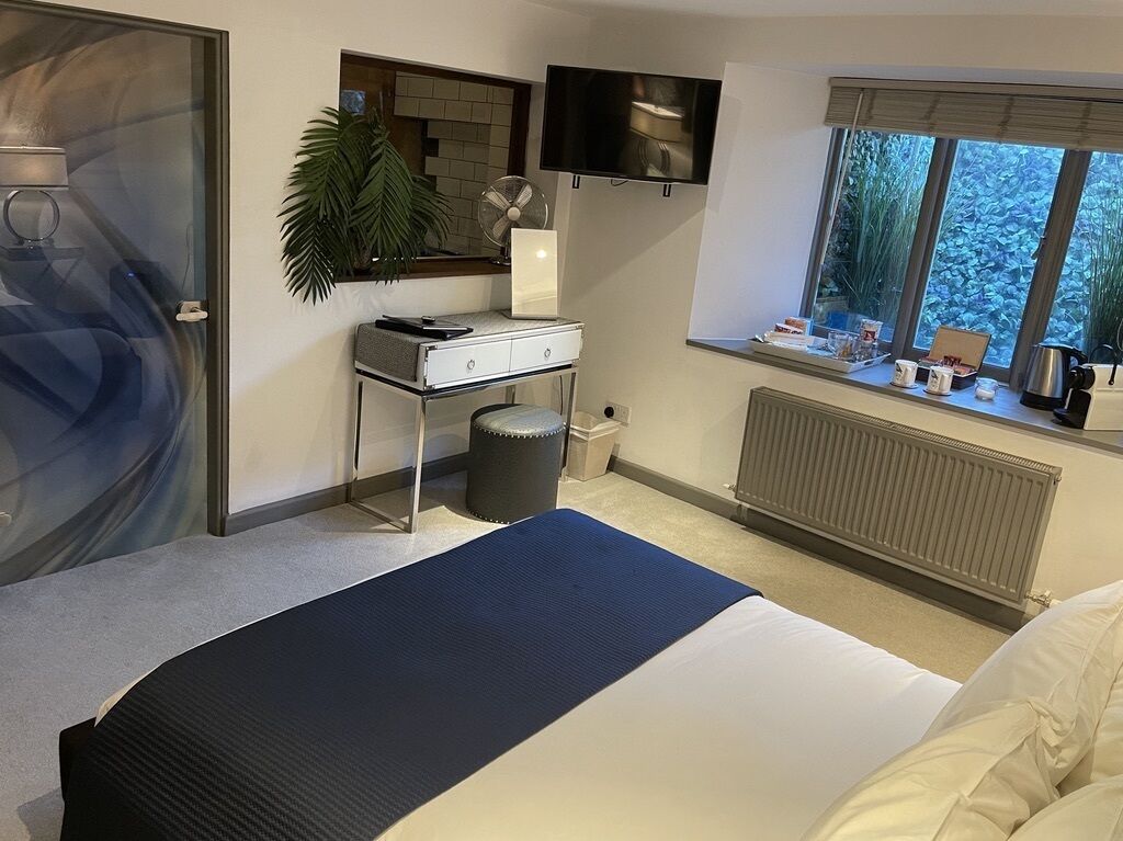 A hotel room with a bed, a desk, a TV, a window with a view, and a radiator.