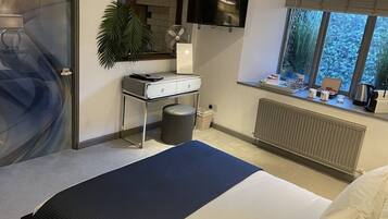A hotel room with a bed, a desk, a TV, a window with a view, and a radiator.