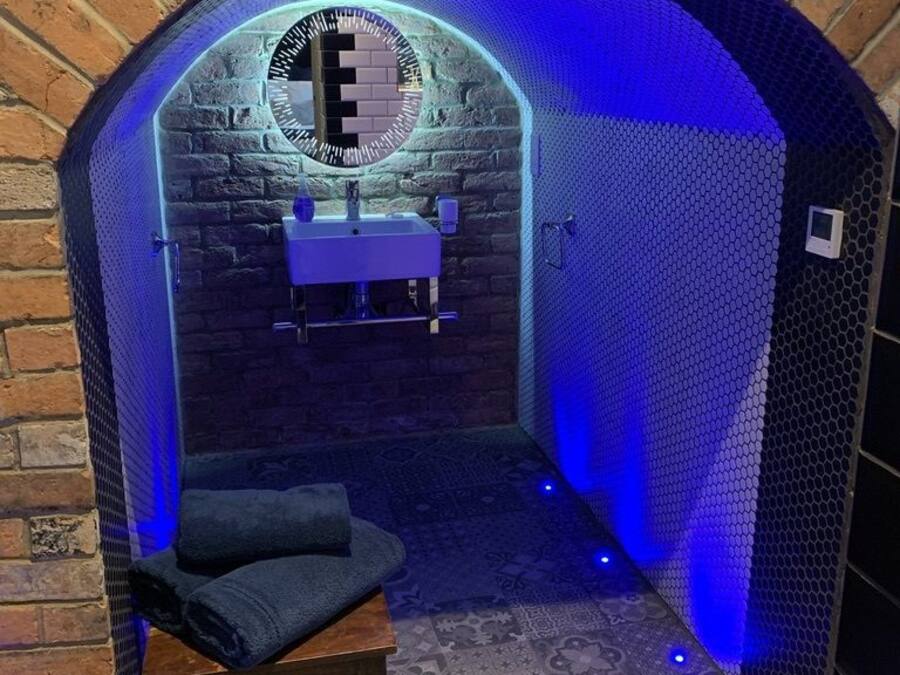 A brick archway leading to a bathroom with a sink and a chair.
