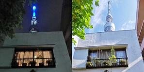A building with a balcony, a window with curtains, and a view of a tower. - Guest House Komatsuya - Hostel (Tokyo)