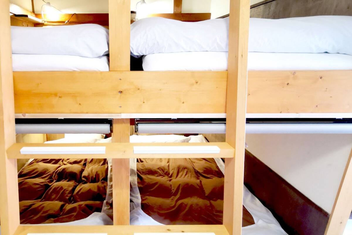 A bunk bed with two levels, each with white bedding.