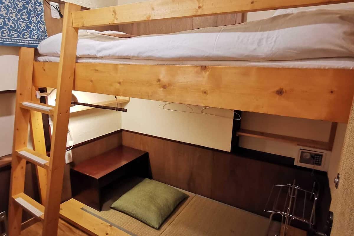 A bunk bed with a wooden ladder, a small shelf, and a green pillow.