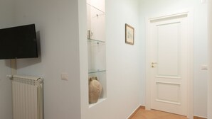 A hallway with a tiled floor, a white door, a framed picture on the wall, and a radiator. - Arbiter Apartments - L'amphora (Napoli)