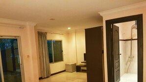 Habitación de hotel con una cama grande, zona de ducha y vistas al exterior.