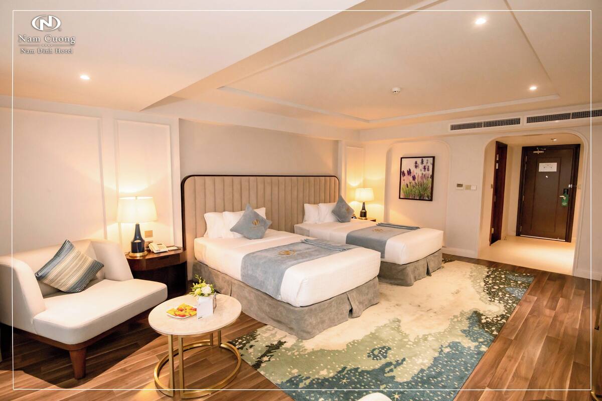 A hotel room with two beds, a sofa, a round coffee table, and a rug.