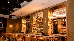 A bar area with multiple seating options, a well-stocked liquor display, and a modern ceiling design. - Nam Cuong Nam Dinh Hotel (Nam Dinh)