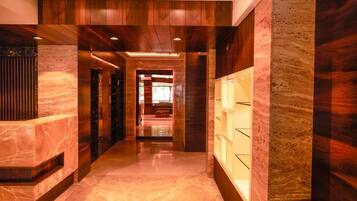 A hallway with a marble floor, wooden paneling, and a glass display case.
