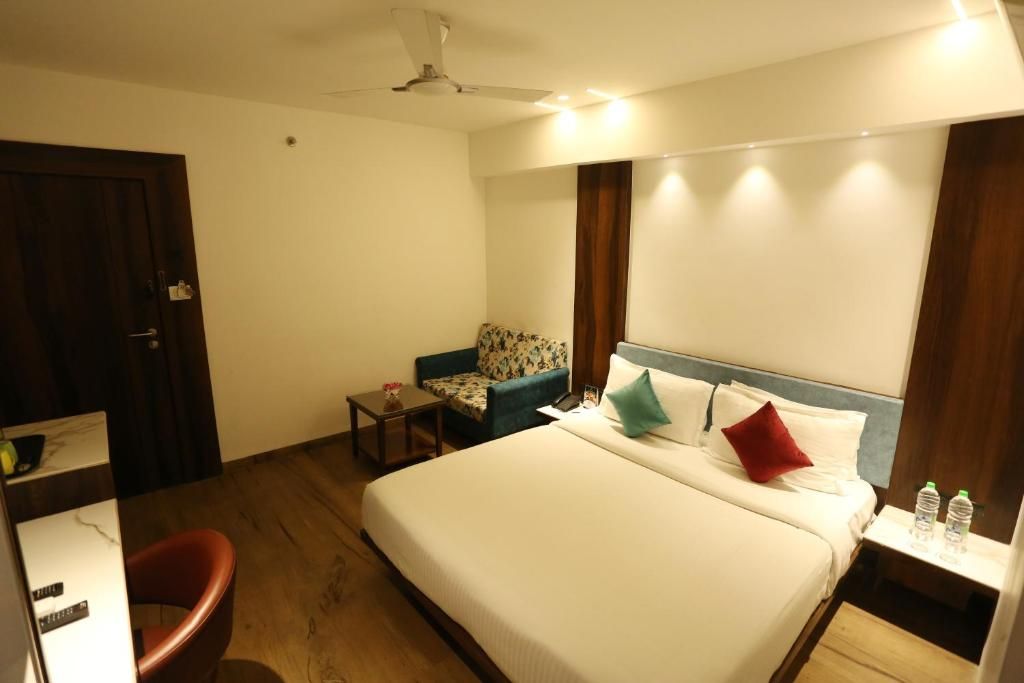 A hotel room with a bed, a chair, a small table, and a nightstand.