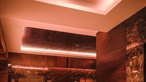 An elevator area with marble walls and a modern light fixture.