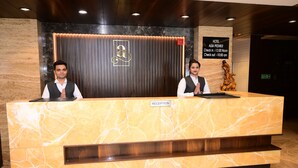 A reception desk with a marble top, a wooden panel backdrop, and a sign indicating hotel name and check-in/out times.