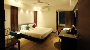 A hotel room with a bed, a desk, a chair, a ceiling fan, and an air conditioning unit.