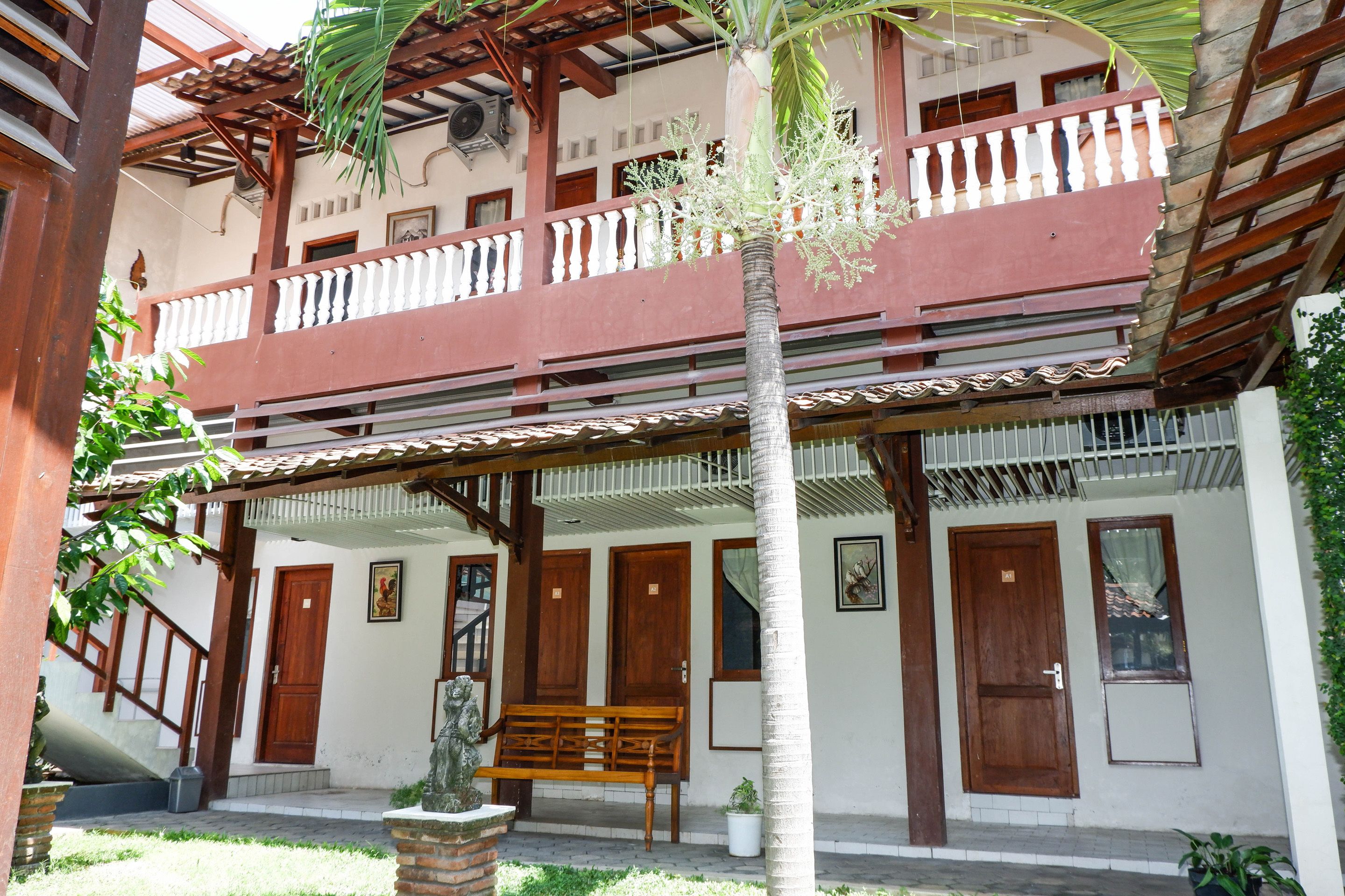 A two-story building with a balcony, wooden doors, and a bench.