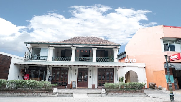 Un bâtiment à deux étages doté d’un balcon, d’une enseigne indiquant « OYO » et d’un auvent rouge.
