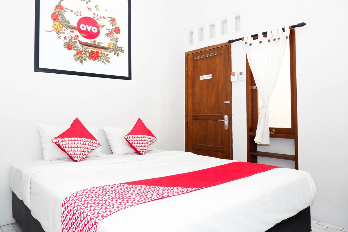 Ein Hotelzimmer mit einem Bett, einer Holztür und einem gerahmten Bild an der Wand.