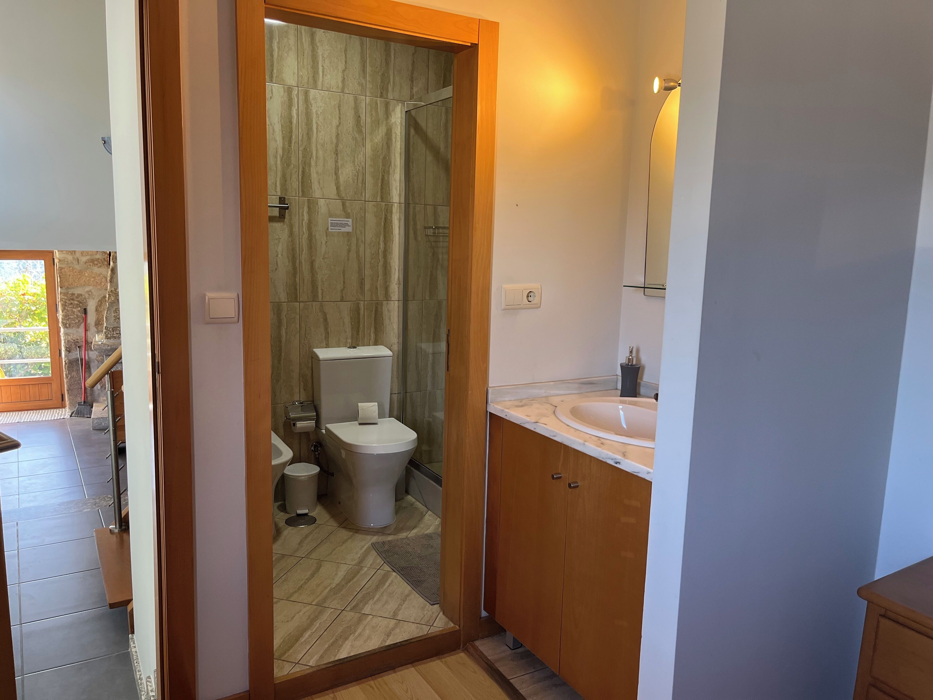 Een moderne badkamer met een marmeren wastafel, houten kastjes en een douchecabine met glazen wanden.