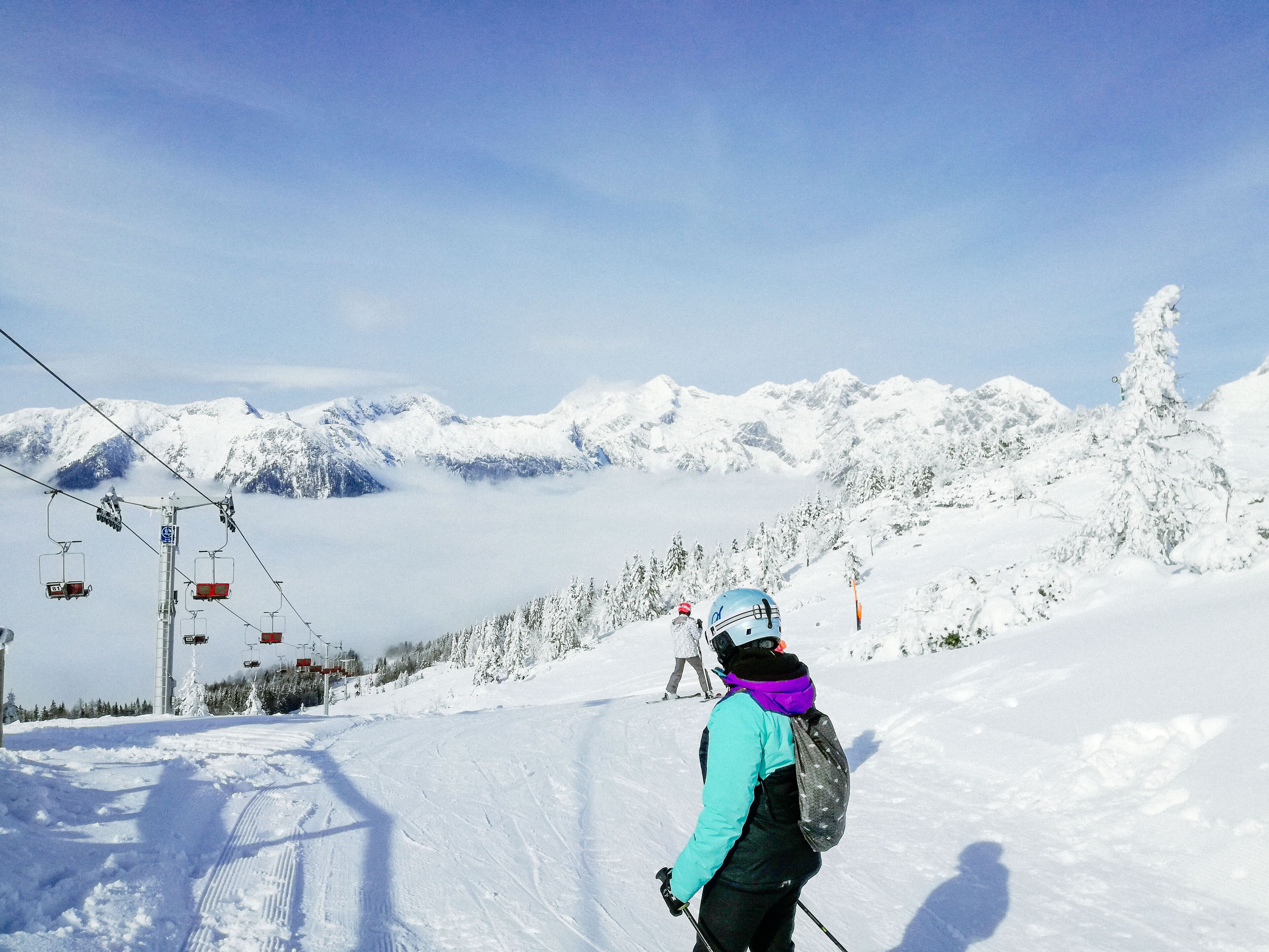 A ski slope with a chairlift and snow-covered mountains in the background.