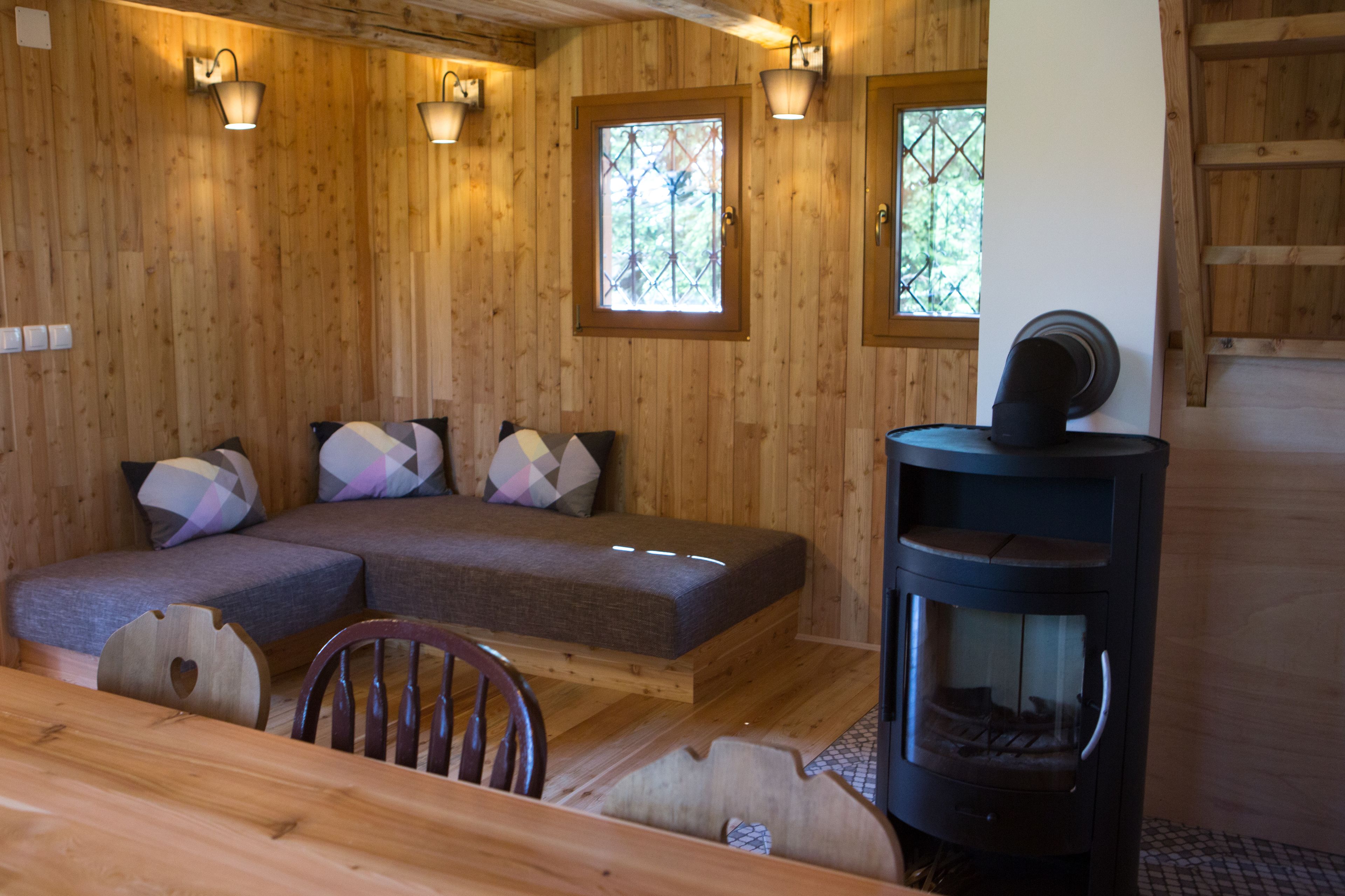 Un interior de madera con un sofá, una mesa de comedor y una estufa de leña.