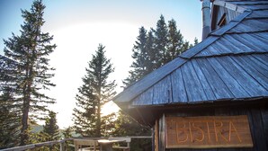 Una cabaña de madera con un letrero que dice "BISTRA" y una terraza con bancos.