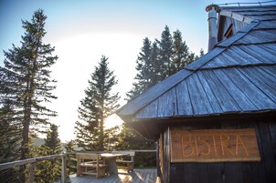 Una cabaña de madera con un letrero que dice "BISTRA" y una terraza con bancos.