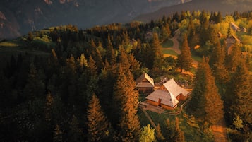 A mountainous landscape with a small cluster of wooden cabins surrounded by dense forest.