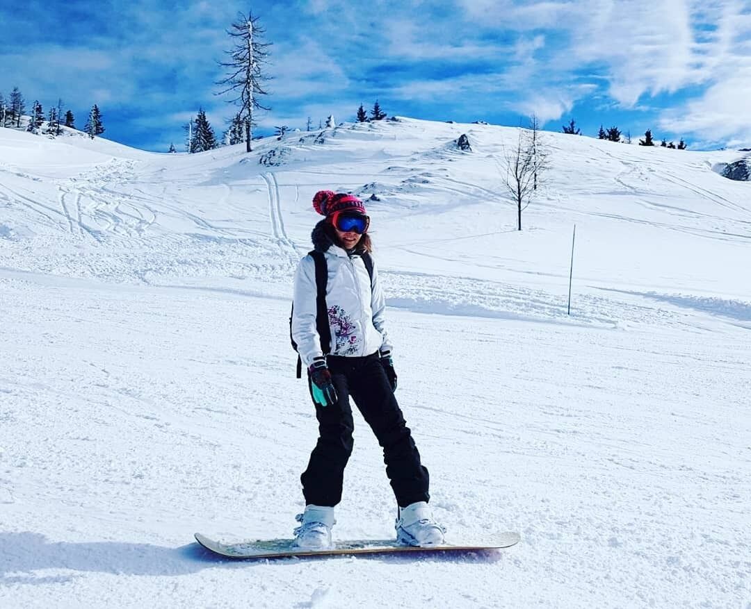 A person snowboarding on a snowy slope with trees in the background.