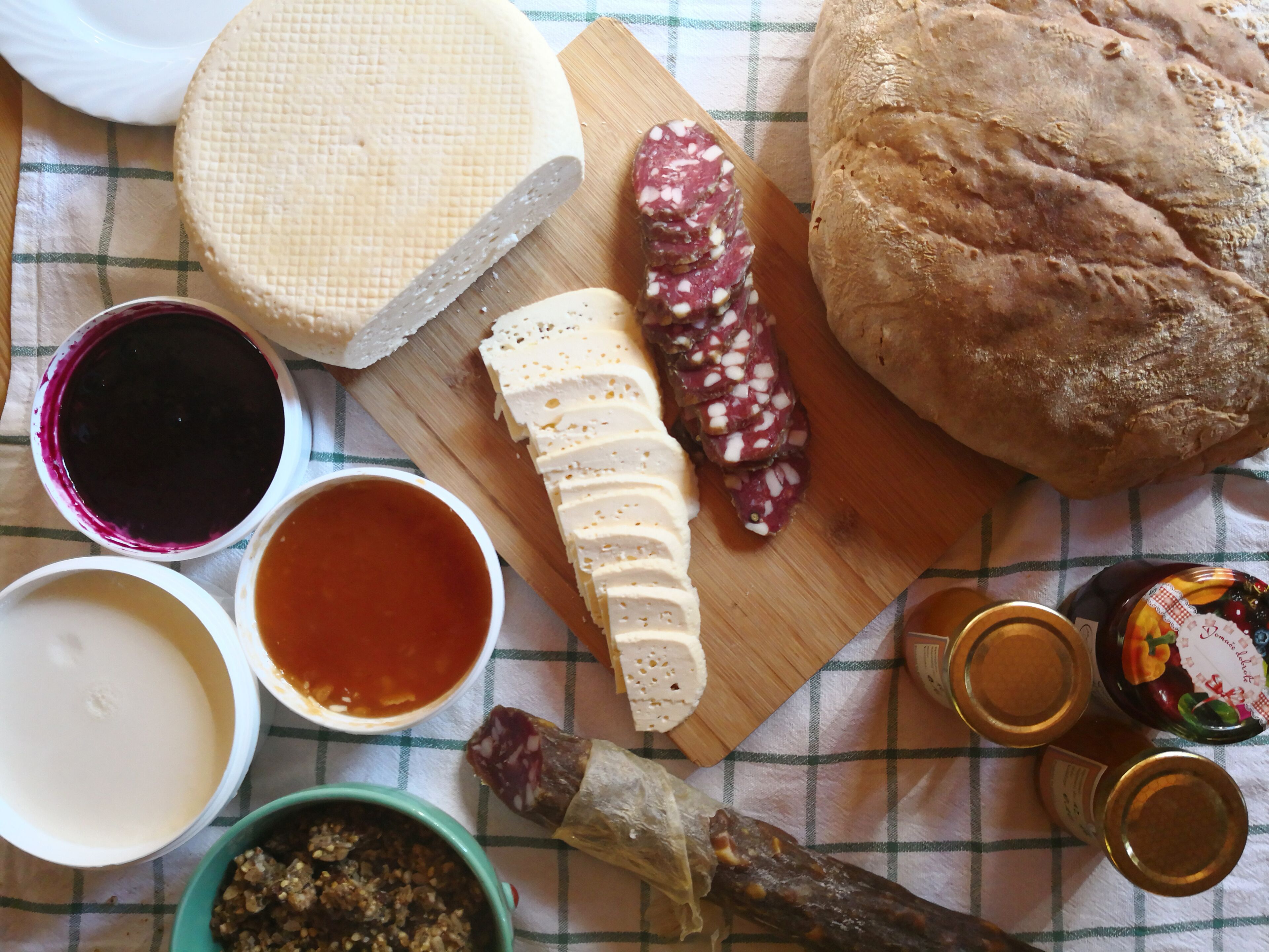 Une variété d’aliments, notamment du fromage, du pain et des condiments, sont disposés sur une table.