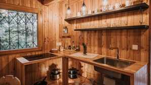 Cocina de cabaña de madera con ventana, repisas de madera y un lavamanos.
