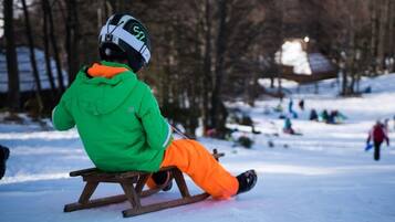 A person sitting on a wooden sled in a snowy outdoor setting.