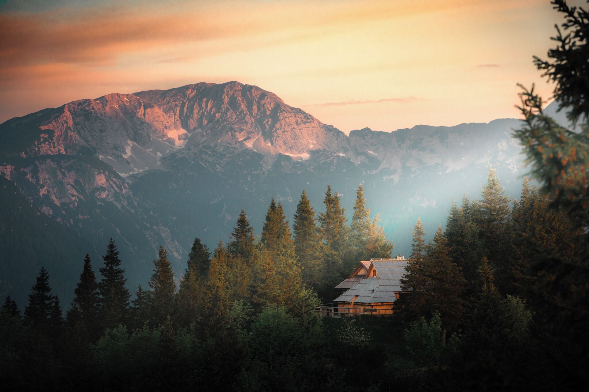 A cabin surrounded by dense forest and mountains.