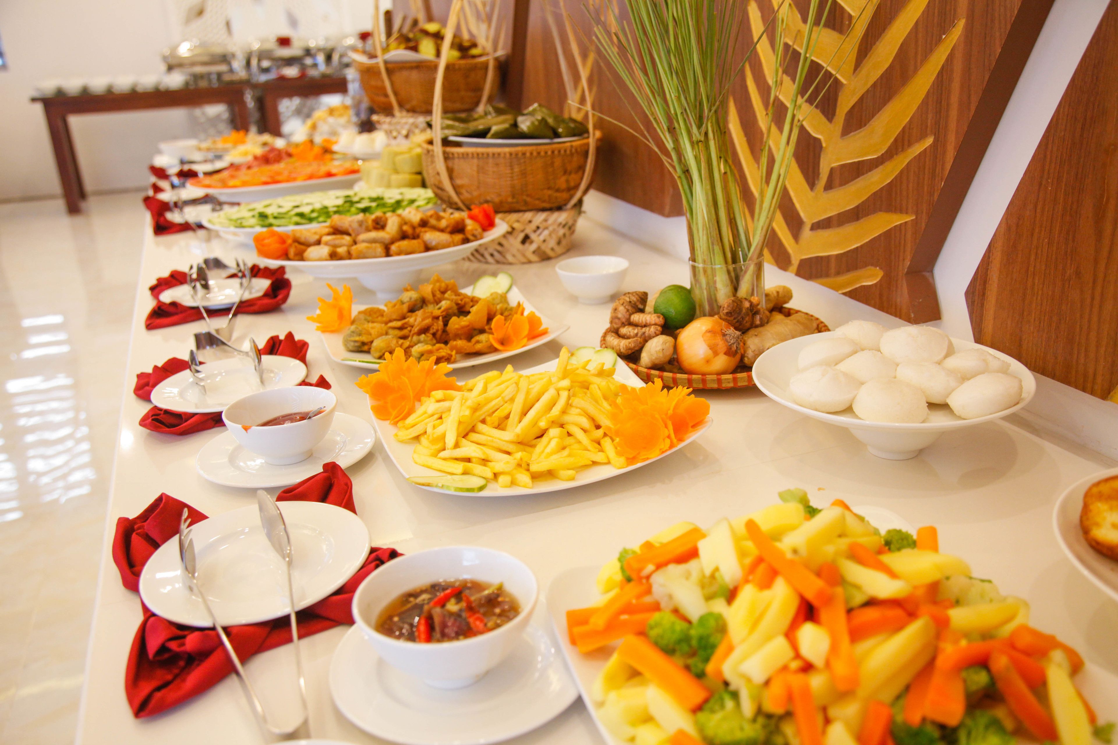 Une table de buffet proposant divers plats, notamment des fruits, des légumes et d’autres aliments.