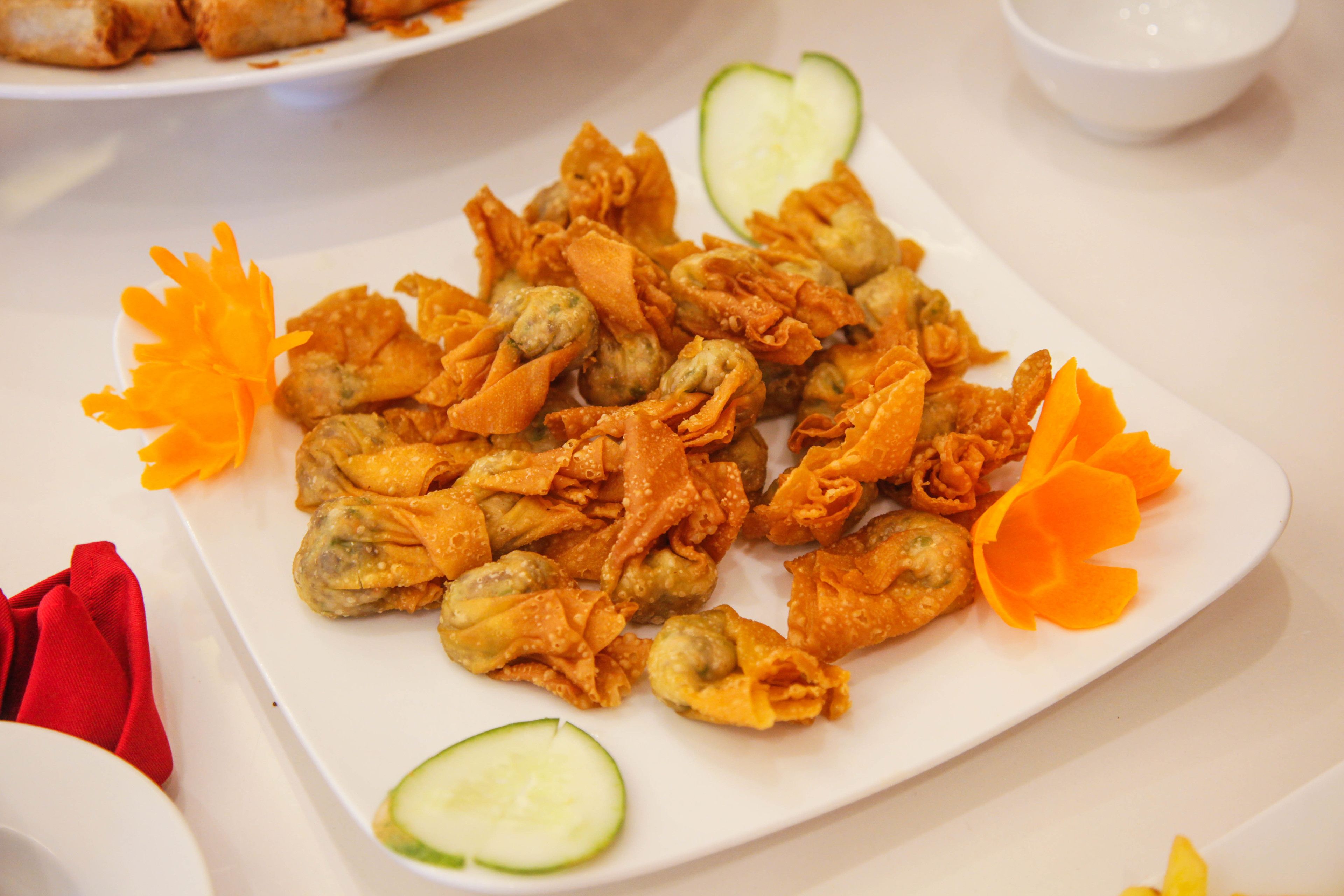 Un plato de comida frita decorado con pétalos de azahar y rodajas de pepino.