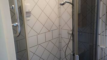 Ducha con cerramiento de vidrio, secamanos y toallero.
