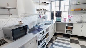 A modern kitchen with stainless steel appliances, white cabinetry, and a checkered floor pattern. - Värdshuset i Motala (Motala)