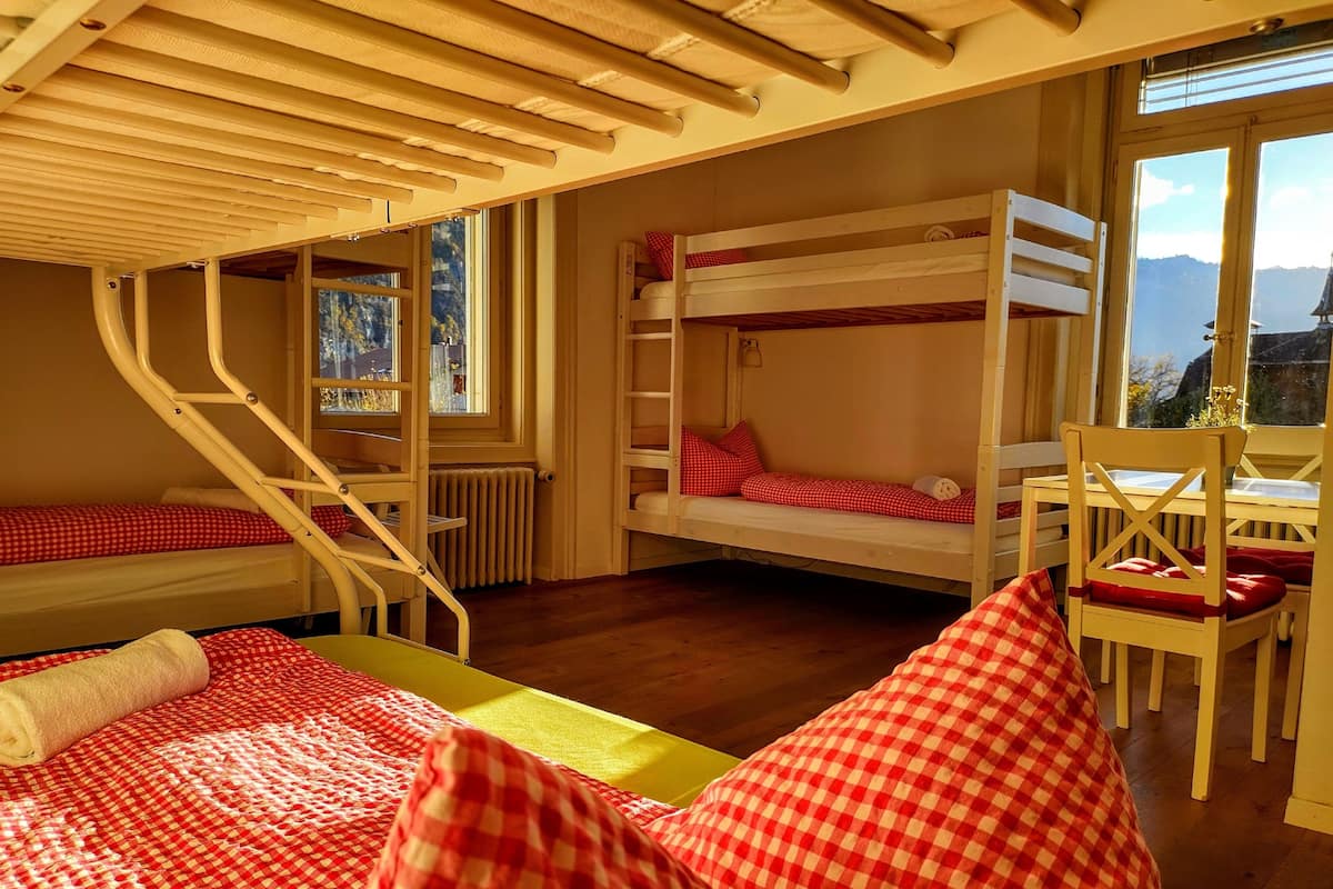 A cozy room with bunk beds, a wooden chair, and a table.