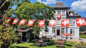 A building with a Swiss flag, outdoor seating, and a garden.