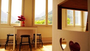 A room with three black stools, a vase with flowers, and large windows with a mountain view.