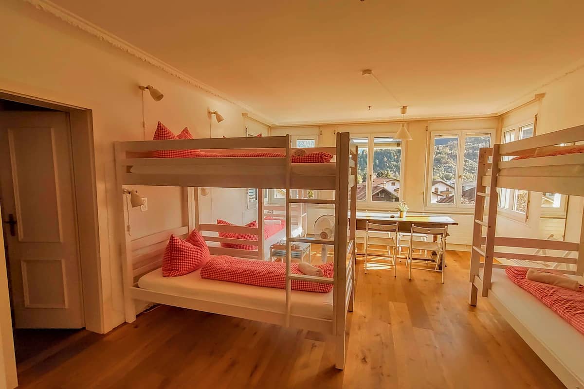 A room with bunk beds, a dining table, and a window with a view.
