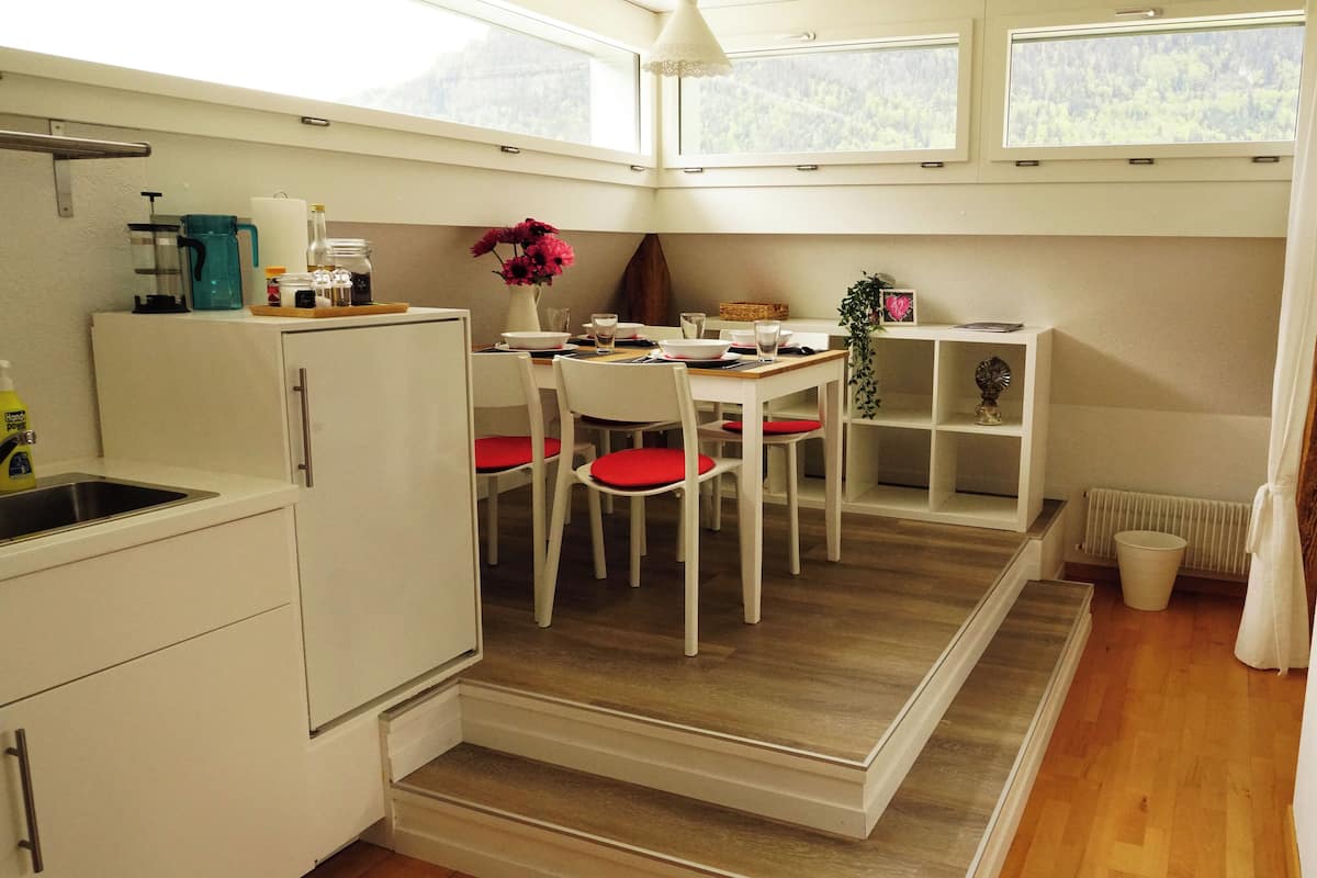 A compact kitchen with a dining area, a sink, and a window with a view of a forest.