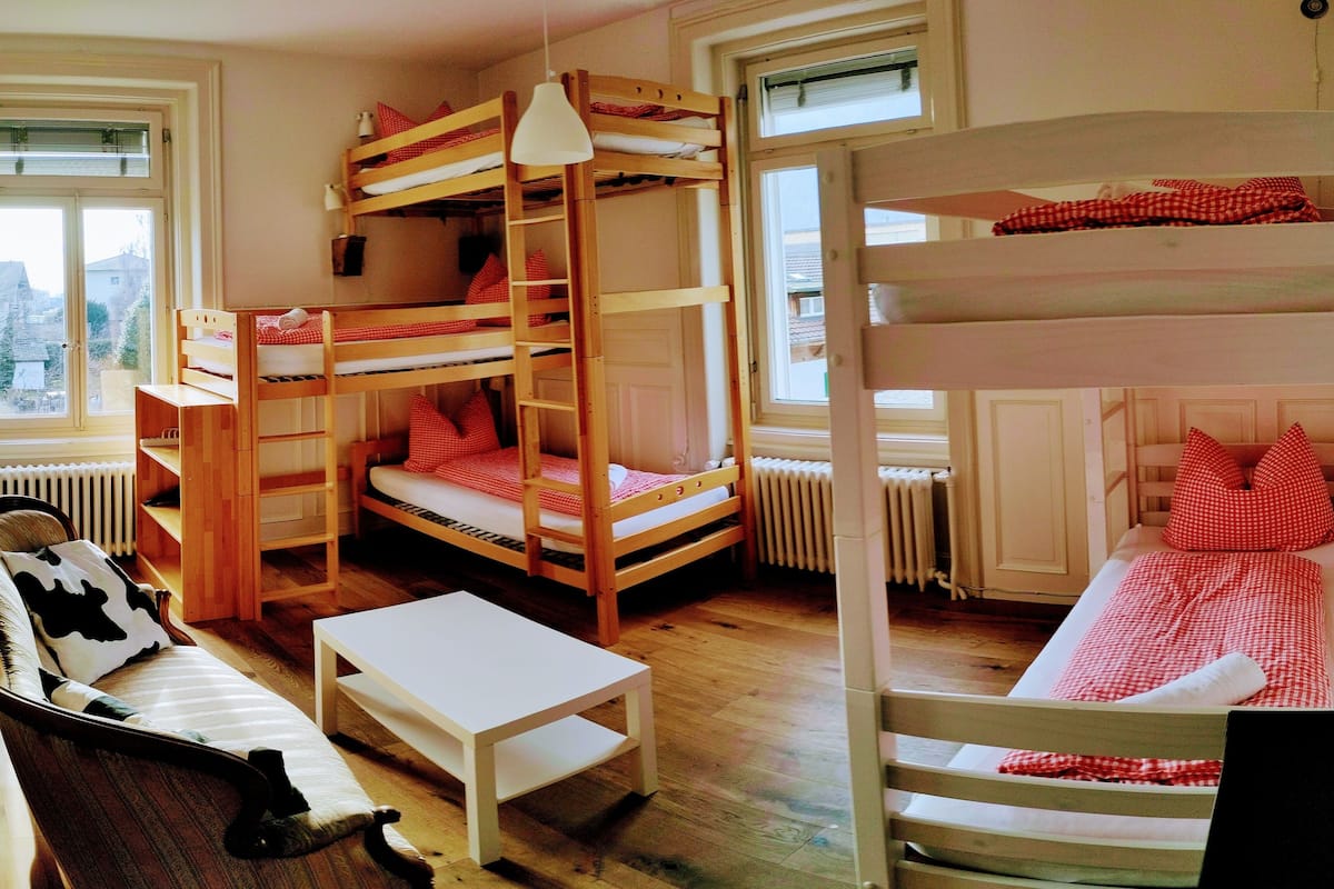 A bunk bed room with a white table and a cow-patterned chair.