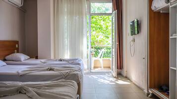 Une chambre d’hôtel avec deux lits, une armoire, une télévision et un balcon donnant sur un espace verdoyant.