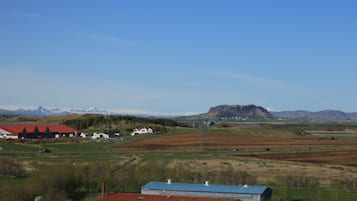 Paesaggio rurale con edifici, campi e montagne.